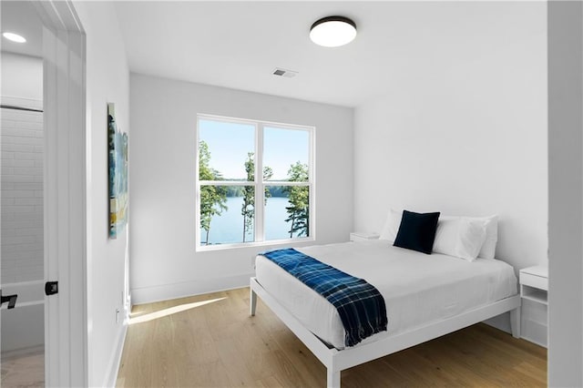 bedroom with a water view and light hardwood / wood-style floors