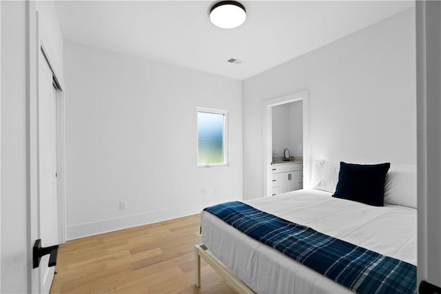bedroom featuring light wood-type flooring, a closet, and connected bathroom