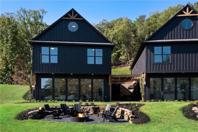 rear view of property featuring a lawn and a fire pit