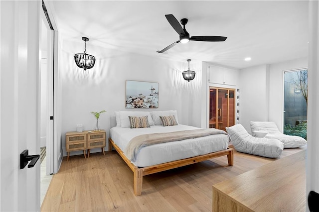 bedroom featuring light hardwood / wood-style floors and ceiling fan with notable chandelier