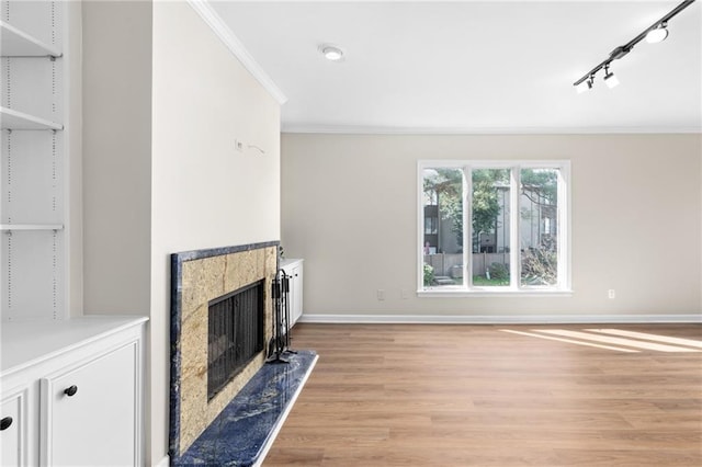 unfurnished living room with light hardwood / wood-style flooring, a high end fireplace, track lighting, and ornamental molding