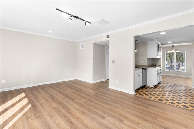 unfurnished living room with light wood-type flooring, rail lighting, an inviting chandelier, and crown molding