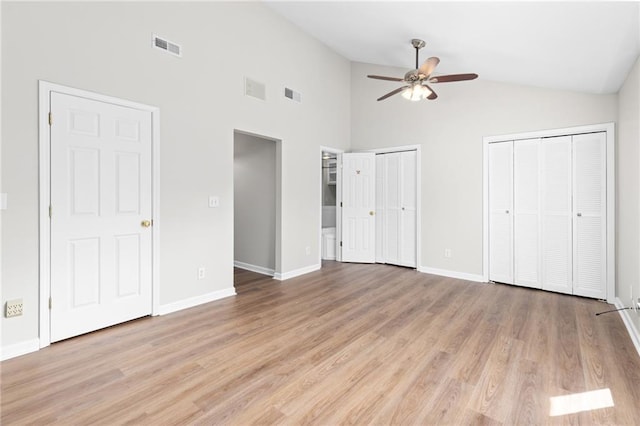 unfurnished bedroom featuring ensuite bath, two closets, light hardwood / wood-style flooring, and ceiling fan