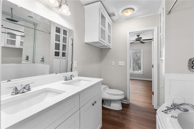 bathroom with vanity, ceiling fan, wood-type flooring, toilet, and a tub