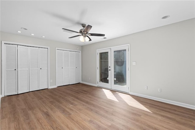 unfurnished bedroom featuring hardwood / wood-style floors, two closets, french doors, ceiling fan, and access to exterior