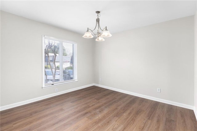 empty room with dark hardwood / wood-style flooring and an inviting chandelier