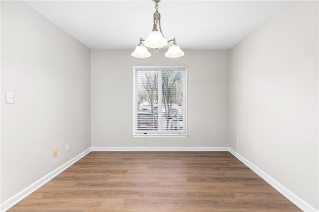 spare room featuring a notable chandelier and wood-type flooring