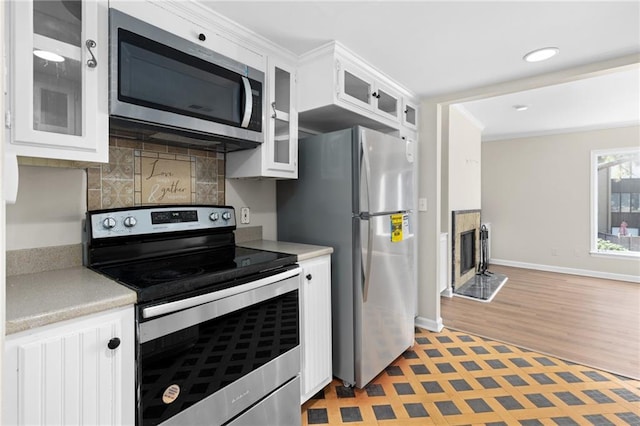 kitchen featuring decorative backsplash, white cabinetry, light hardwood / wood-style floors, and appliances with stainless steel finishes