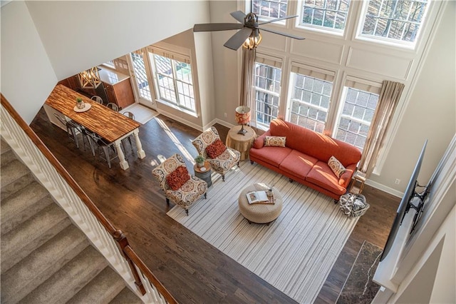 living room featuring dark hardwood / wood-style floors, a towering ceiling, and ceiling fan