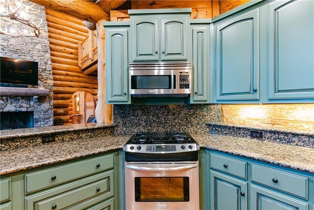 kitchen with a fireplace, stainless steel appliances, backsplash, rustic walls, and blue cabinets