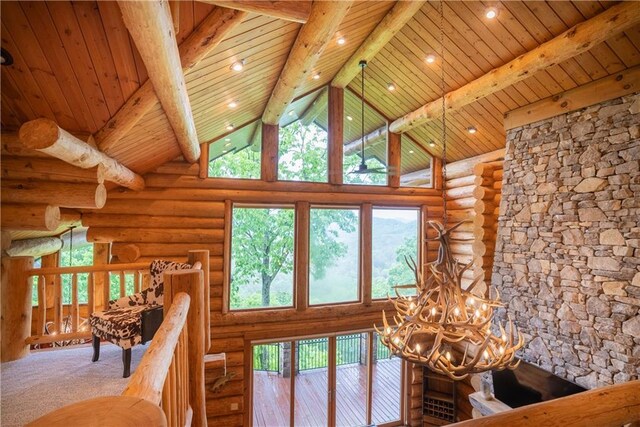 interior space with beam ceiling, wood ceiling, a chandelier, rustic walls, and carpet