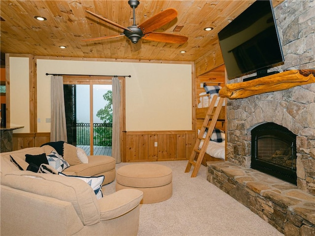 carpeted living room featuring wood walls, ceiling fan, wood ceiling, and a fireplace