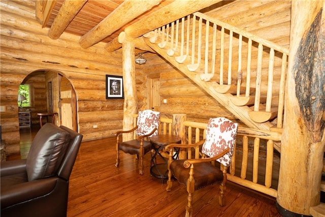 living area featuring beam ceiling, log walls, hardwood / wood-style flooring, and wooden ceiling