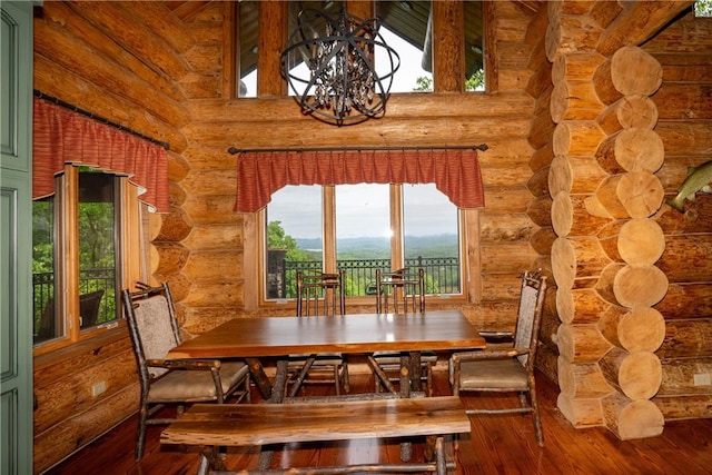 dining area featuring a chandelier, wood-type flooring, and log walls