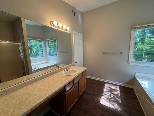 full bathroom with a healthy amount of sunlight, visible vents, a bath, and wood finished floors