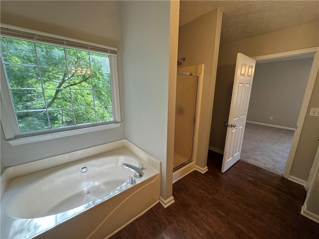 bathroom with a garden tub, baseboards, wood finished floors, and a stall shower