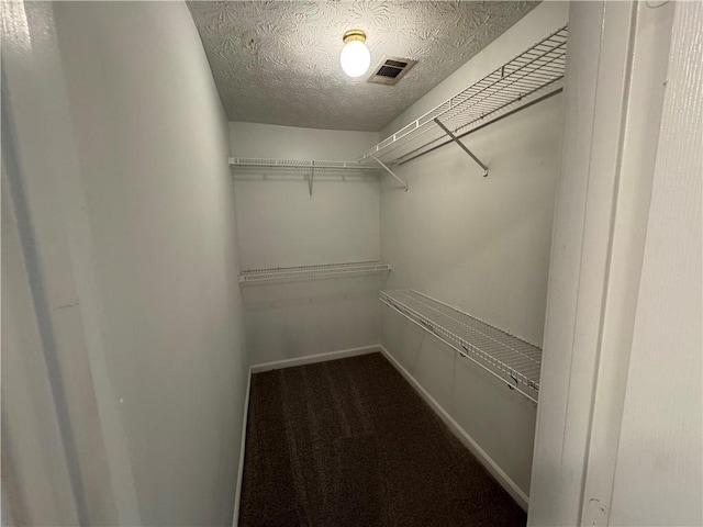 walk in closet with visible vents and dark colored carpet