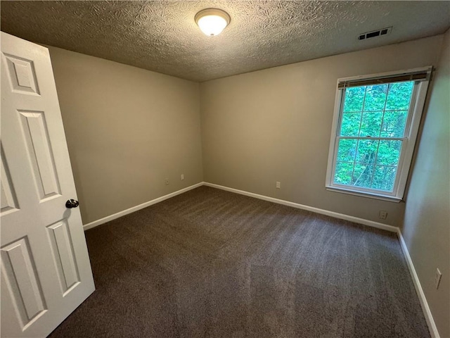 empty room featuring a textured ceiling, visible vents, baseboards, and dark colored carpet