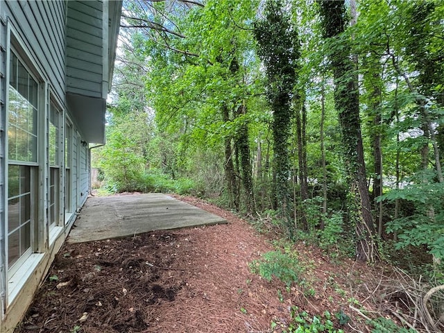 view of yard with a wooded view and a patio