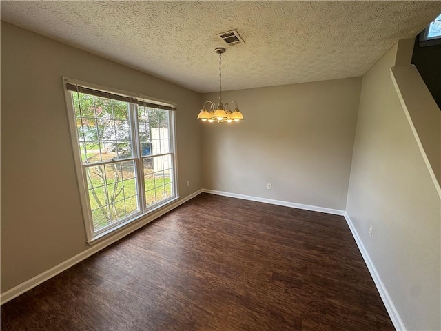 unfurnished dining area featuring a textured ceiling, a chandelier, visible vents, and dark wood-style floors