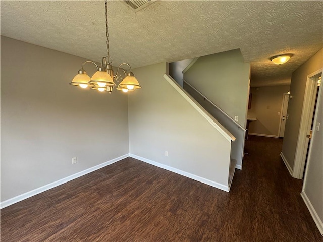 unfurnished room featuring an inviting chandelier, wood finished floors, a textured ceiling, visible vents, and baseboards