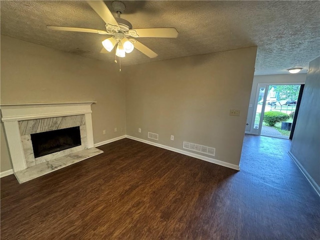 unfurnished living room featuring a textured ceiling, visible vents, dark wood-type flooring, and a high end fireplace