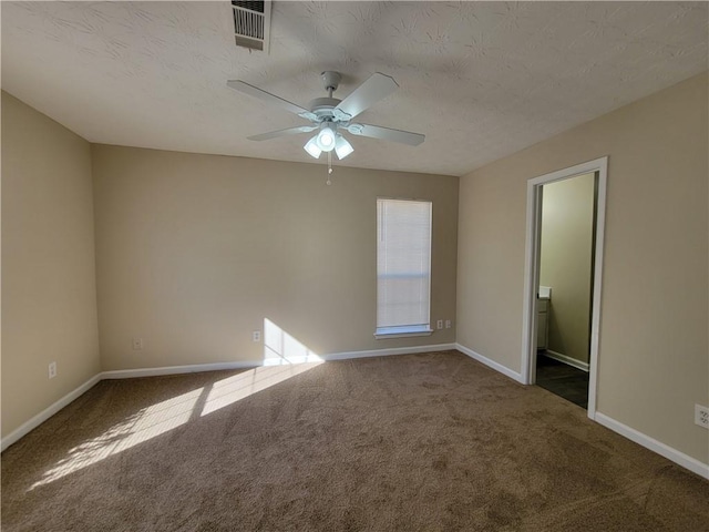 carpeted spare room featuring baseboards, a textured ceiling, visible vents, and a ceiling fan