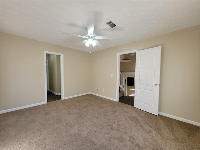 empty room featuring a ceiling fan, carpet, visible vents, and baseboards