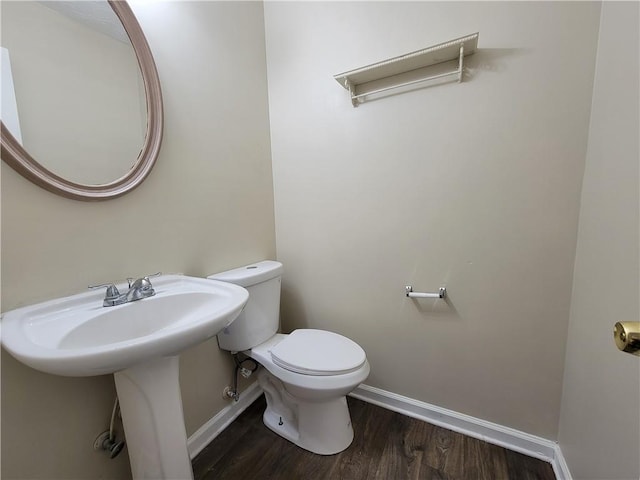 bathroom featuring baseboards, a sink, toilet, and wood finished floors