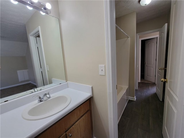 full bathroom with wood finished floors, shower / washtub combination, a textured ceiling, and vanity