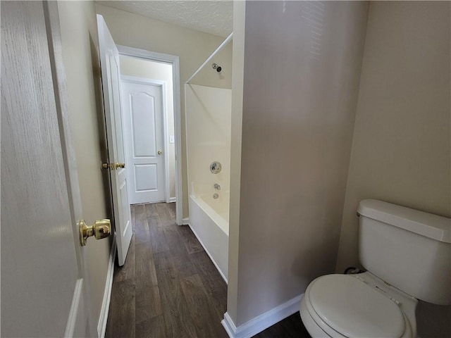 full bath featuring shower / bathing tub combination, toilet, a textured ceiling, wood finished floors, and baseboards