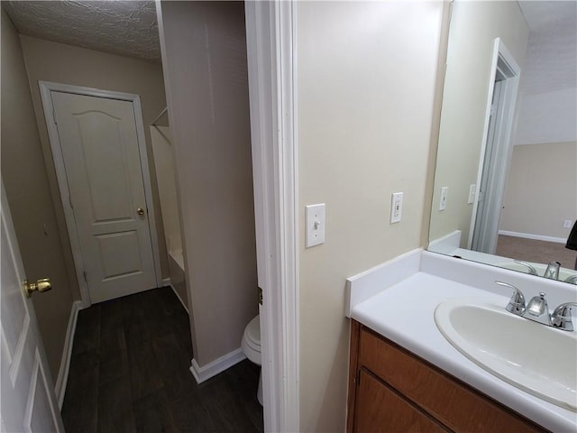 bathroom with bathing tub / shower combination, toilet, vanity, wood finished floors, and baseboards