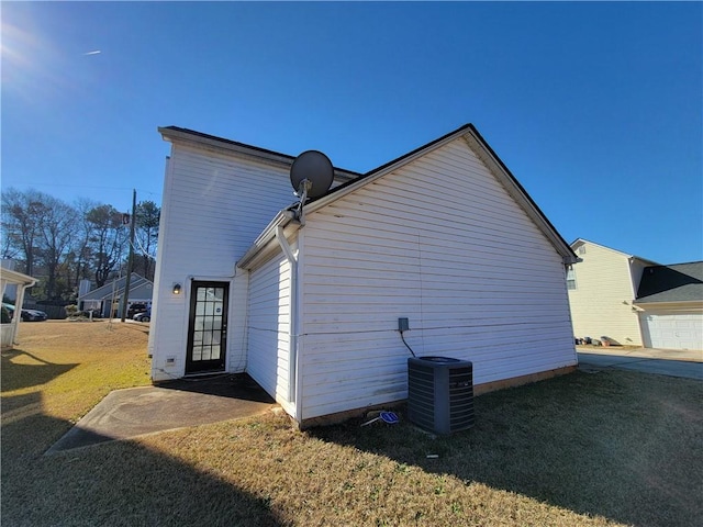 view of side of home featuring cooling unit and a lawn