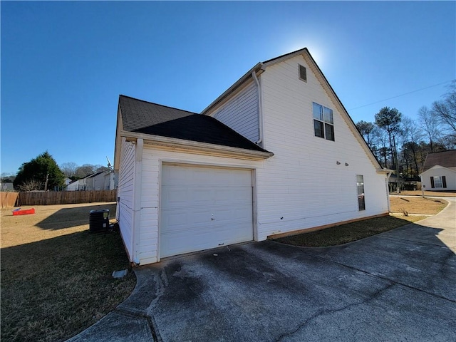 view of side of property featuring a yard, central AC, fence, a garage, and driveway