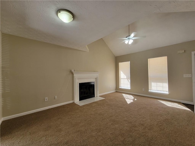 unfurnished living room with lofted ceiling, a fireplace with flush hearth, carpet flooring, ceiling fan, and baseboards