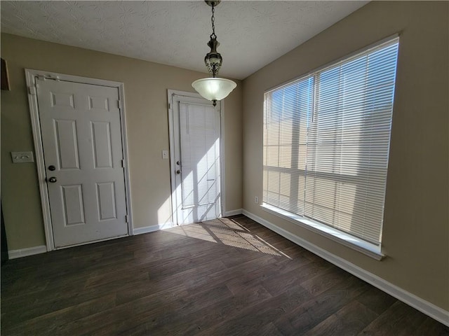 interior space featuring a textured ceiling, dark wood finished floors, and baseboards