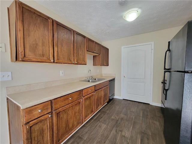 kitchen with dishwashing machine, a sink, light countertops, freestanding refrigerator, and dark wood finished floors