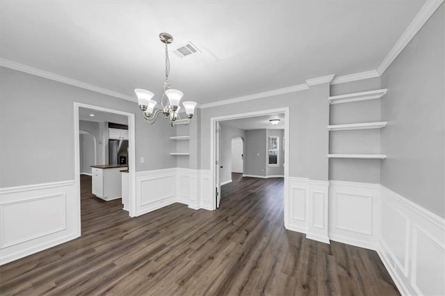 unfurnished dining area with built in features, dark wood-type flooring, crown molding, and a notable chandelier