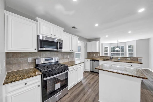 kitchen featuring white cabinets, hardwood / wood-style floors, sink, a kitchen island, and appliances with stainless steel finishes