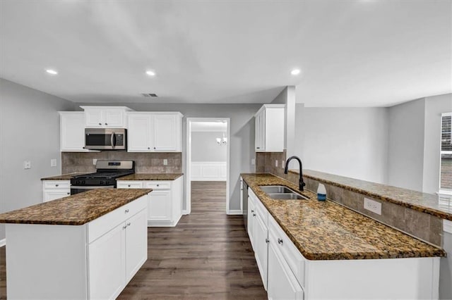 kitchen featuring white cabinetry, sink, kitchen peninsula, appliances with stainless steel finishes, and dark hardwood / wood-style flooring