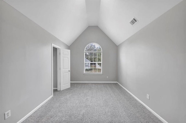 carpeted empty room with vaulted ceiling