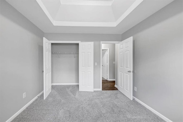 unfurnished bedroom with a closet, a tray ceiling, and light colored carpet