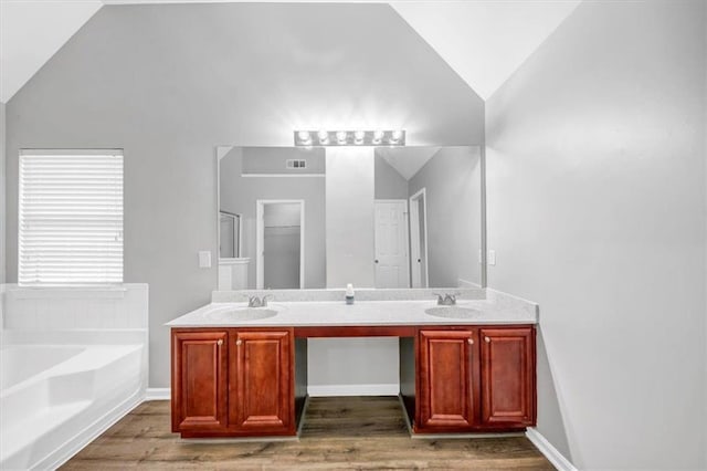 bathroom with hardwood / wood-style floors, a bathtub, lofted ceiling, and vanity