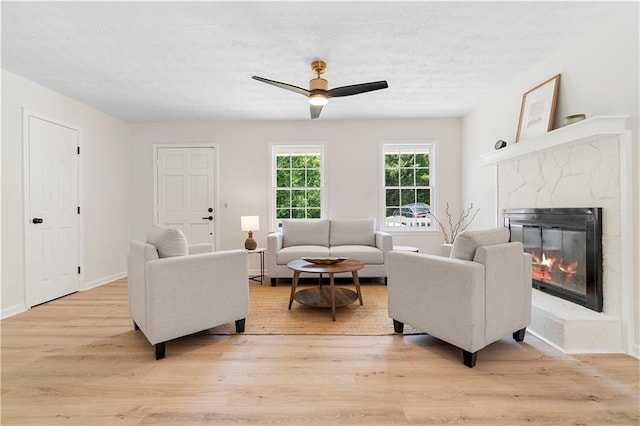 6273 Oak Ridge Dr, Flowery Branch, GA 30542 - living room with light wood-style flooring, ceiling fan, a high end fireplace, a textured ceiling, and baseboards