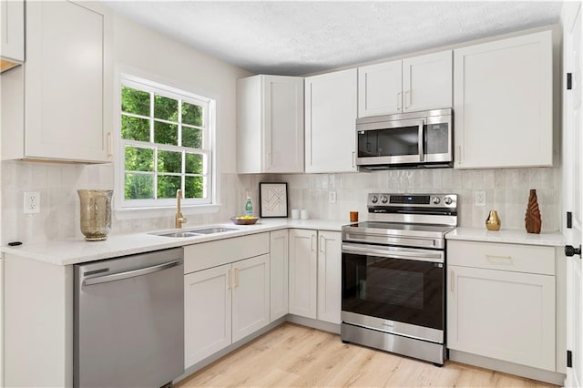 6273 Oak Ridge Dr, Flowery Branch, GA 30542 - kitchen with stainless steel appliances, a sink, light countertops, light wood-style floors, and decorative backsplash