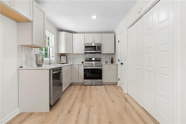 6273 Oak Ridge Dr, Flowery Branch, GA 30542 - kitchen featuring appliances with stainless steel finishes, light wood finished floors, backsplash, light countertops, and a sink