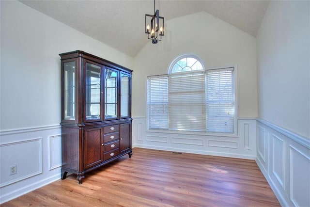 dining area featuring a chandelier, lofted ceiling, and light wood-type flooring