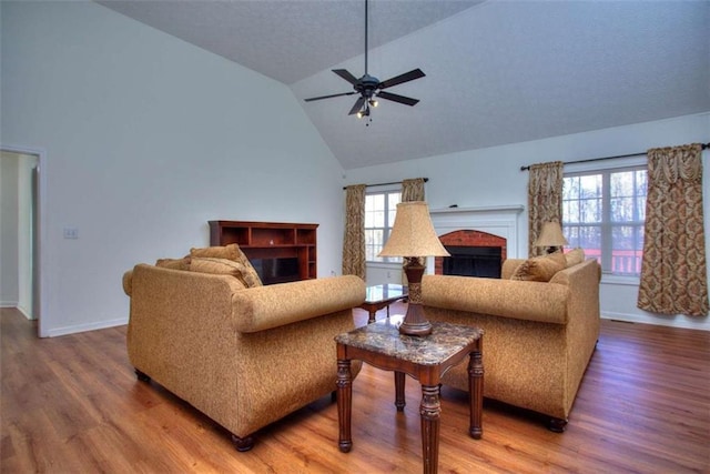 living room featuring a fireplace, hardwood / wood-style floors, vaulted ceiling, and ceiling fan