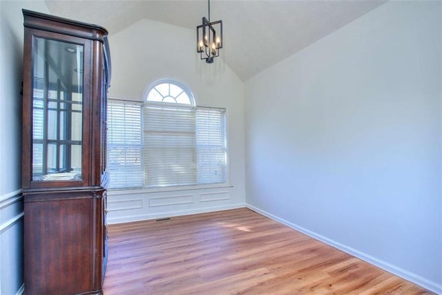 unfurnished dining area with lofted ceiling, light hardwood / wood-style flooring, and an inviting chandelier