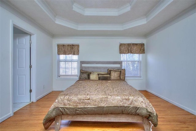 bedroom with a tray ceiling, hardwood / wood-style floors, and ornamental molding